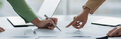 Two people pointing at a document while reviewing it